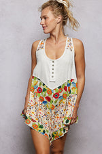 Woman wearing a white tank top with colorful floral skirt against a gray background