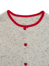 Close-up of a textured sweater with red trim and buttons on a white background