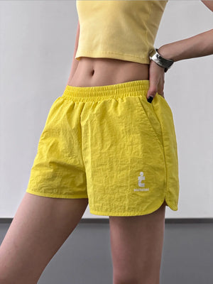 Person wearing yellow shorts with a logo on a plain background