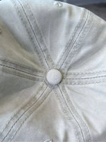 Close-up of a beige cap with a button on a blurred background