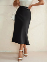 Person wearing a black skirt and white top against a light background