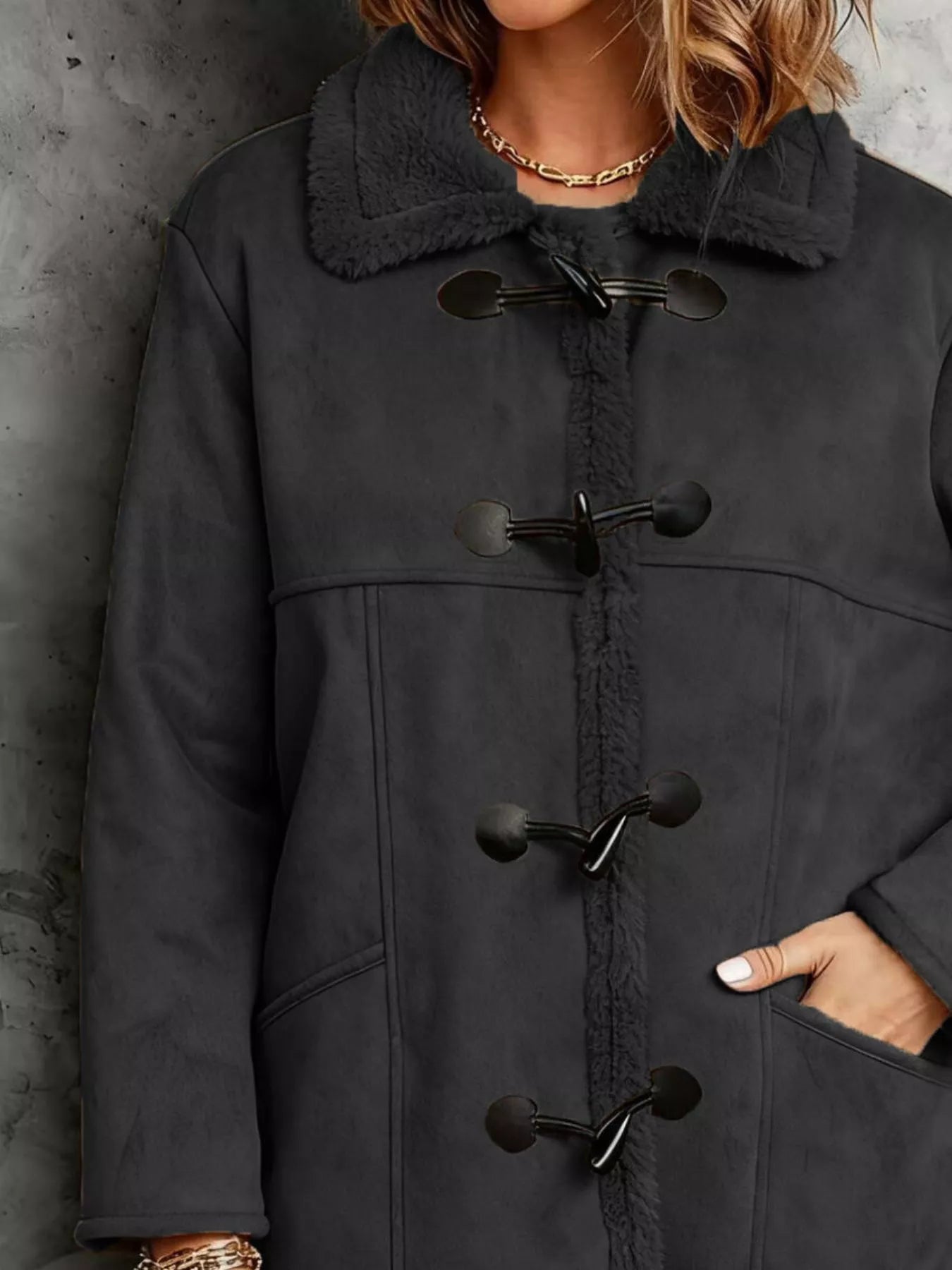 Black duffle coat with black buttons on a textured gray background