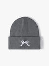 Gray knit beanie with a white bow design on a light gray background