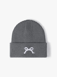 Gray knit beanie with a white bow design on a light gray background
