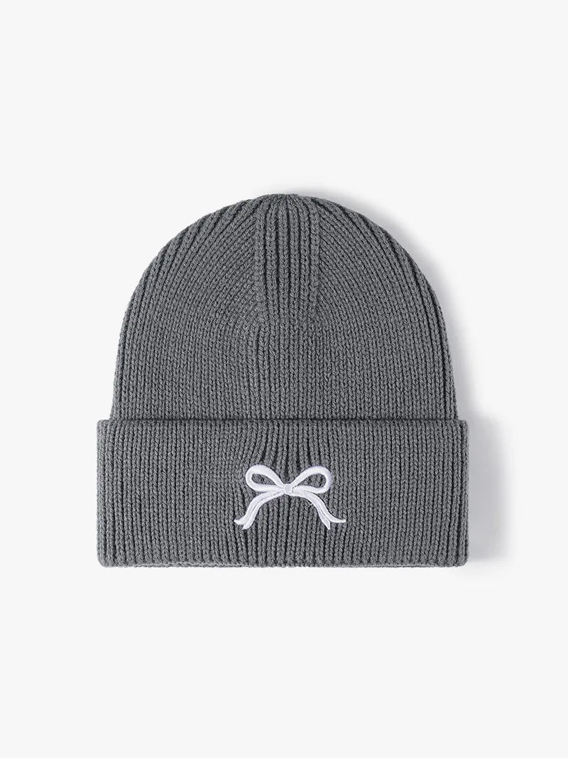 Gray knit beanie with a white bow design on a light gray background