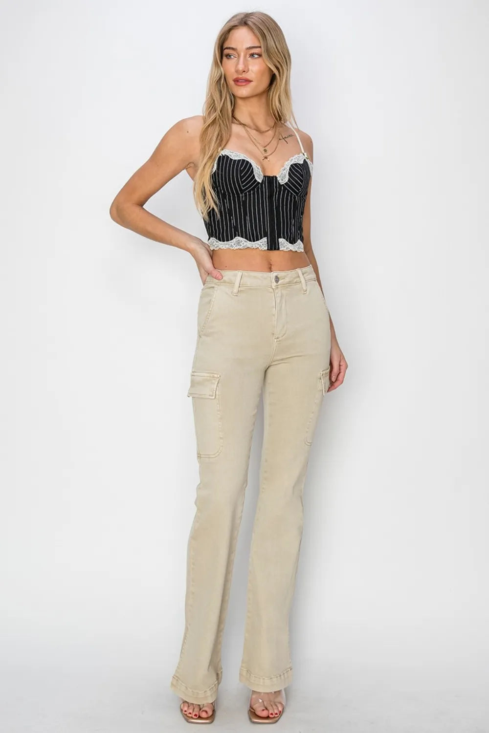 Woman wearing a black and white striped top and beige flared jeans on a white background