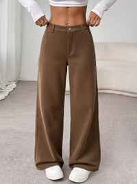 Brown wide-leg pants worn by a person in a neutral indoor setting