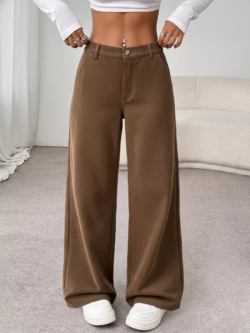 Brown wide-leg pants worn by a person in a neutral indoor setting