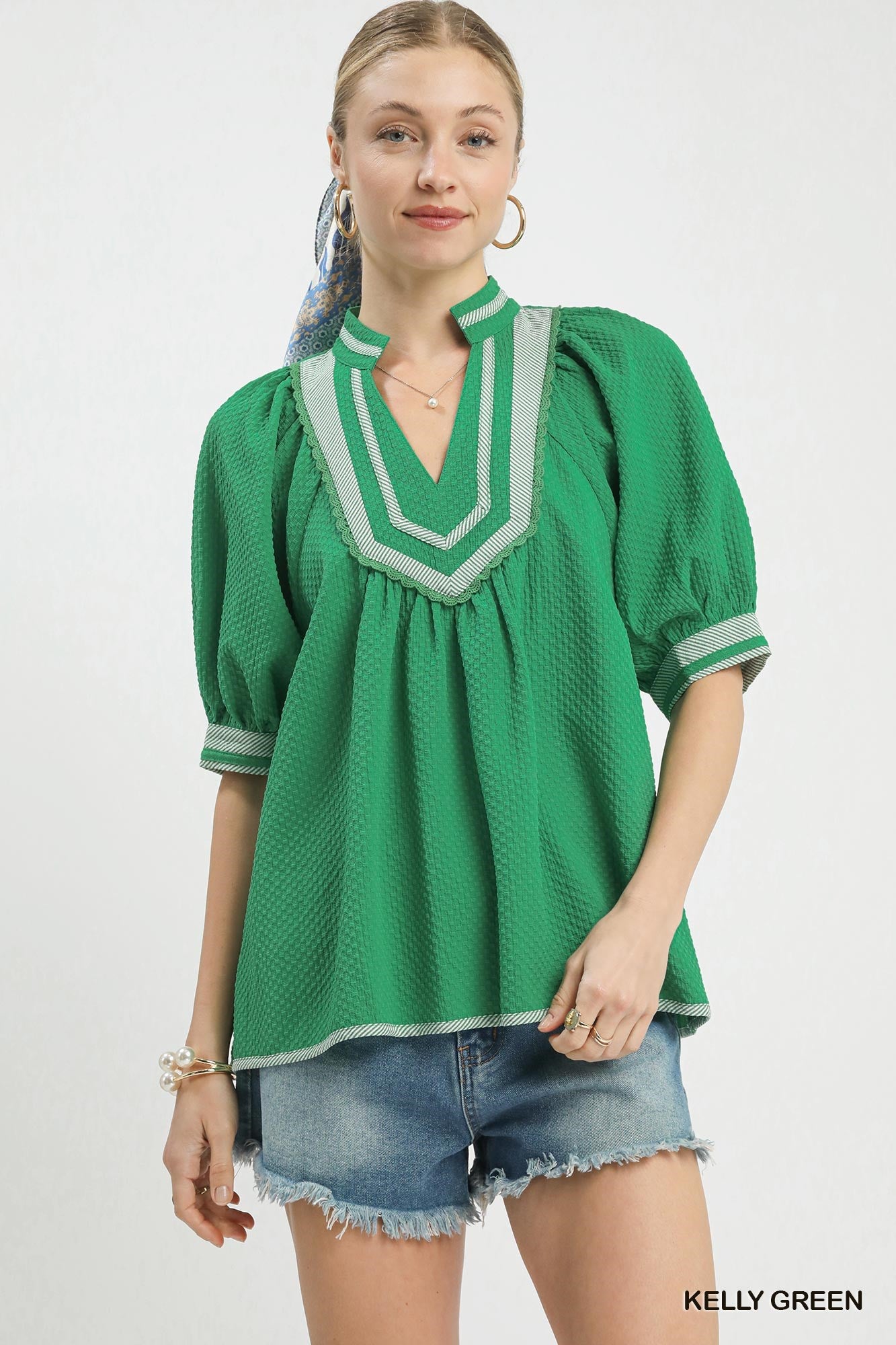 Woman wearing a green blouse with white trim on a white background