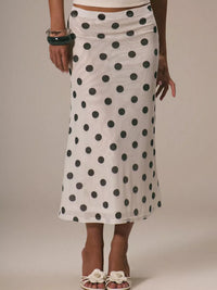Person wearing a white skirt with black polka dots on a plain background