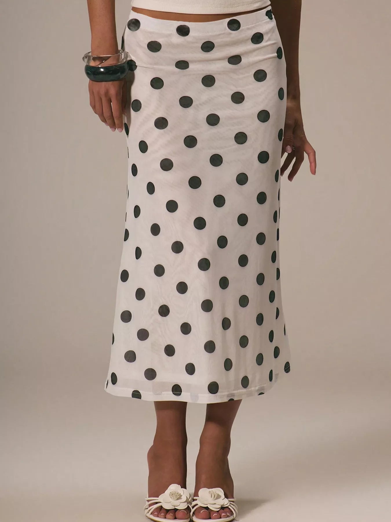 Person wearing a white skirt with black polka dots on a plain background