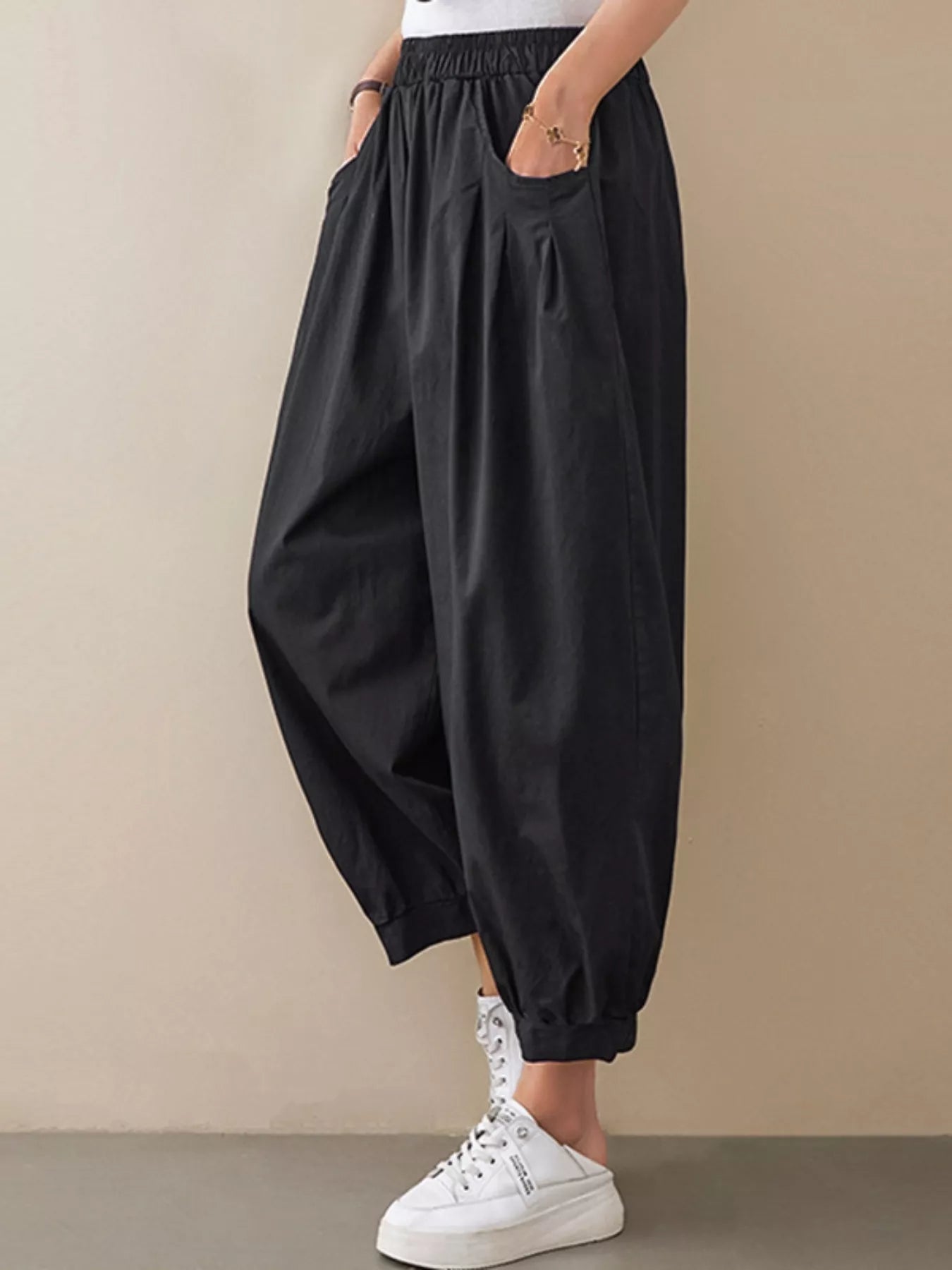 Black wide-leg pants worn by a person on a beige background