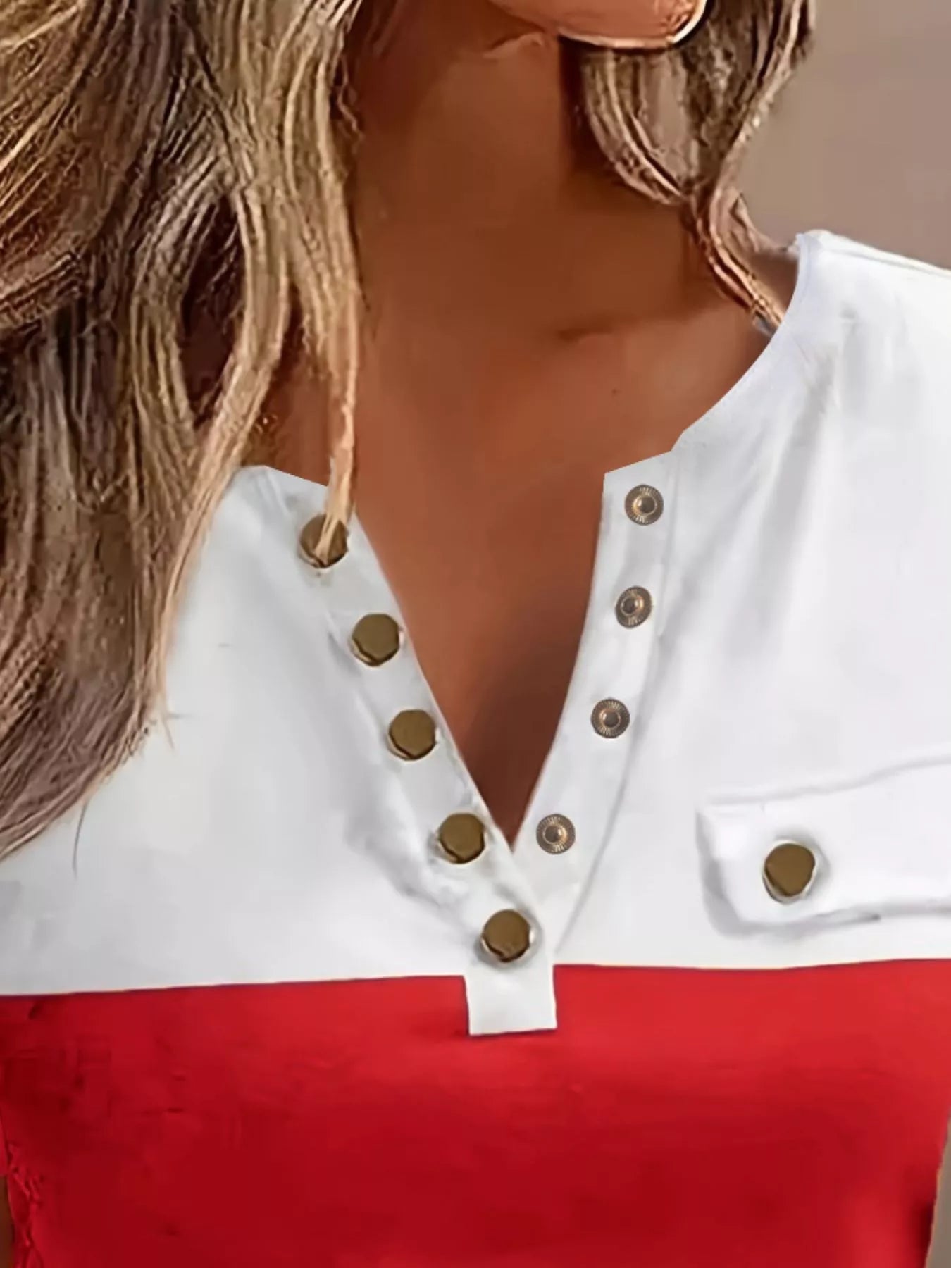 Close-up of a white top with gold buttons and red fabric, worn by a person.