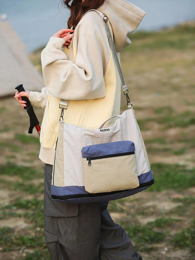 Person holding a beige and blue bag outdoors