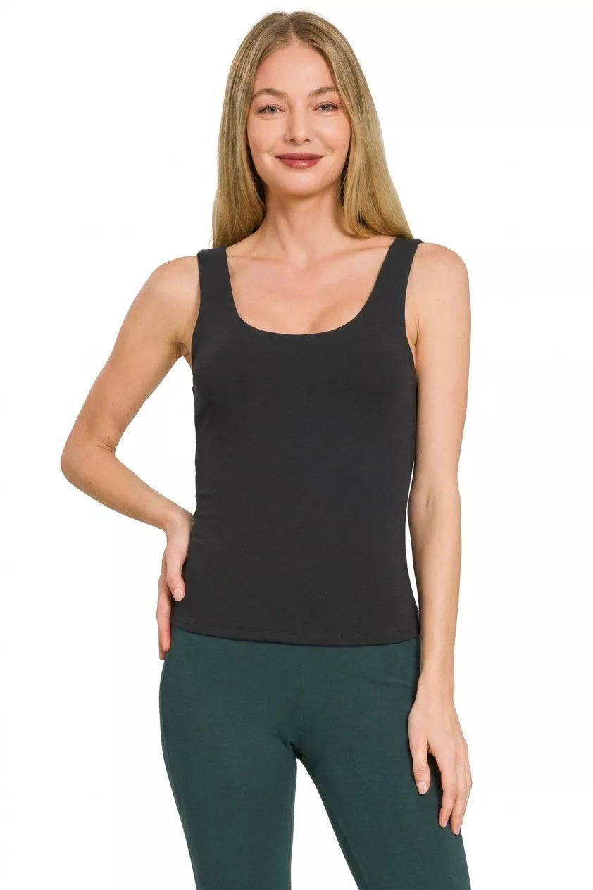 Woman wearing a black tank top and green pants on a white background