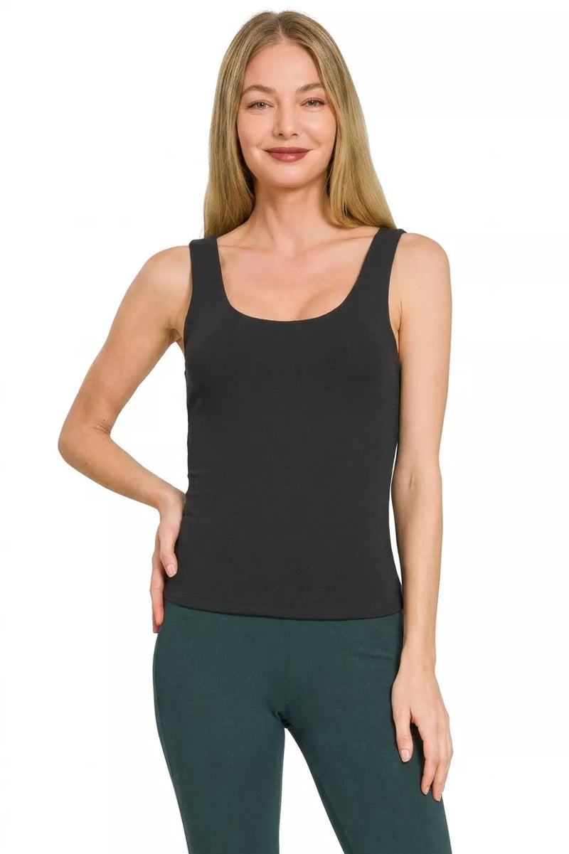 Woman wearing a black tank top and green pants on a white background