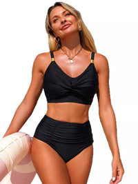 Woman wearing a black bikini with gold straps on a white background