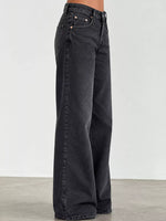 A person wearing dark charcoal gray wide-leg denim jeans, shown from the waist down against a plain light gray studio background.