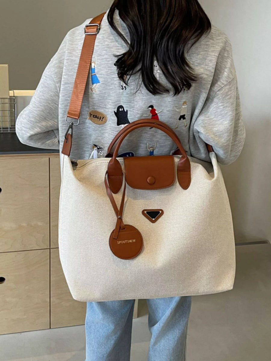 Person holding a beige tote bag with brown handles and accents in a kitchen setting