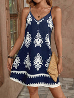 Woman wearing a navy blue dress with white patterns, holding a straw clutch.