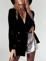 Woman wearing a black blazer and silver skirt with a plain background