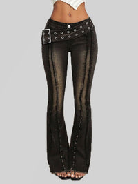 Black flared jeans with studded details on a gray background