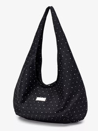 Black shoulder bag with white polka dots on a light gray background