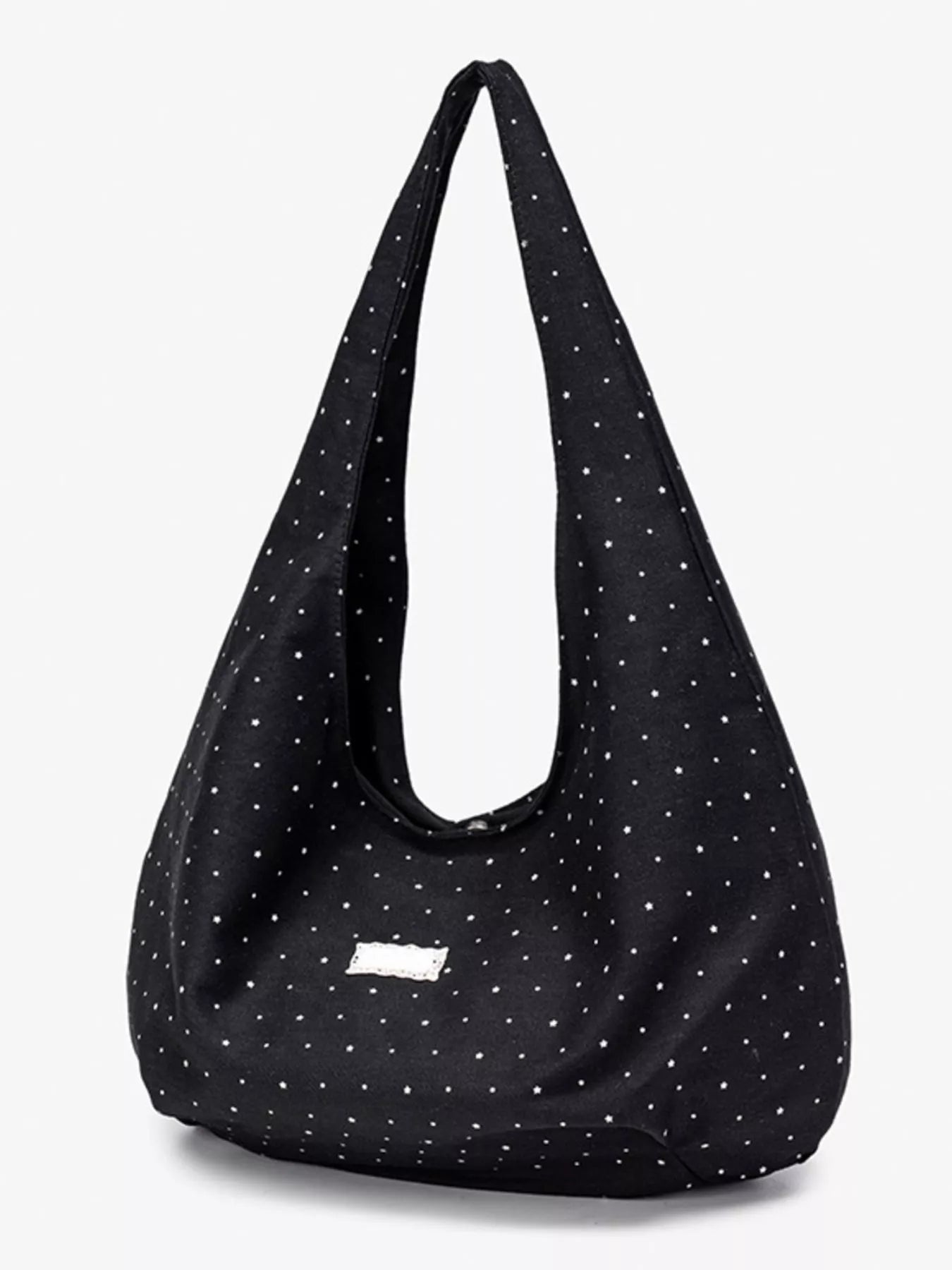Black shoulder bag with white polka dots on a light gray background