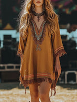 Woman wearing a mustard yellow dress with intricate patterns and fringes at an outdoor event.