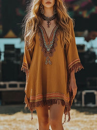 Woman wearing a mustard yellow dress with intricate patterns and fringes at an outdoor event.