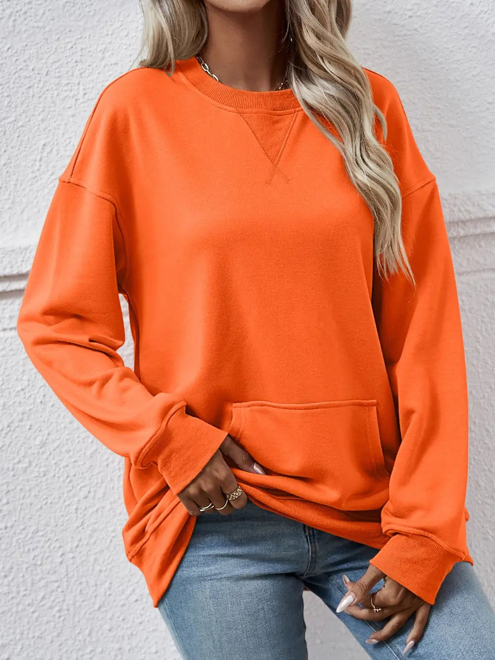 Person wearing an orange sweatshirt with a neutral background