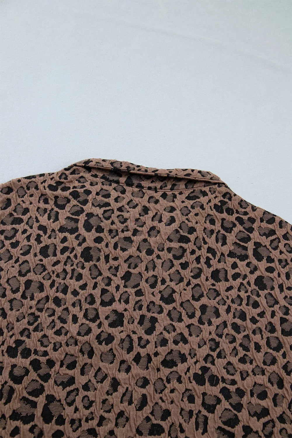 Leopard print pattern on a textured surface with a light blue background