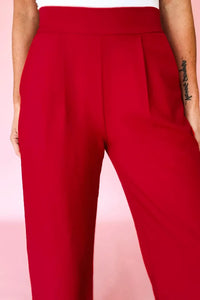 Red pants worn by a person on a pink background
