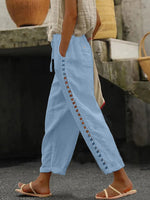 Light blue pants with decorative cut-out sides worn by a person, standing outdoors.