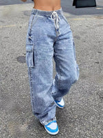 Person wearing acid-wash jeans and blue sneakers on a street.
