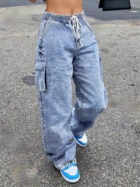 Person wearing acid-wash jeans and blue sneakers on a street.