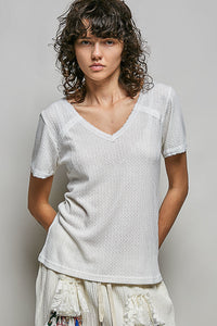 Woman wearing a textured white top against a plain background