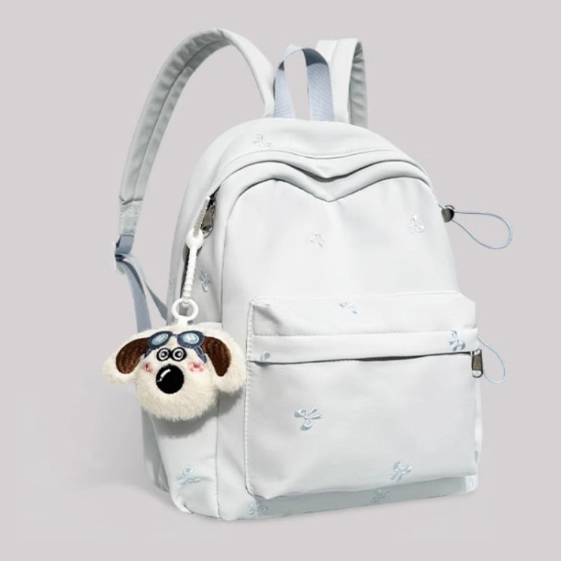Light blue backpack with a dog-shaped keychain on a light gray background