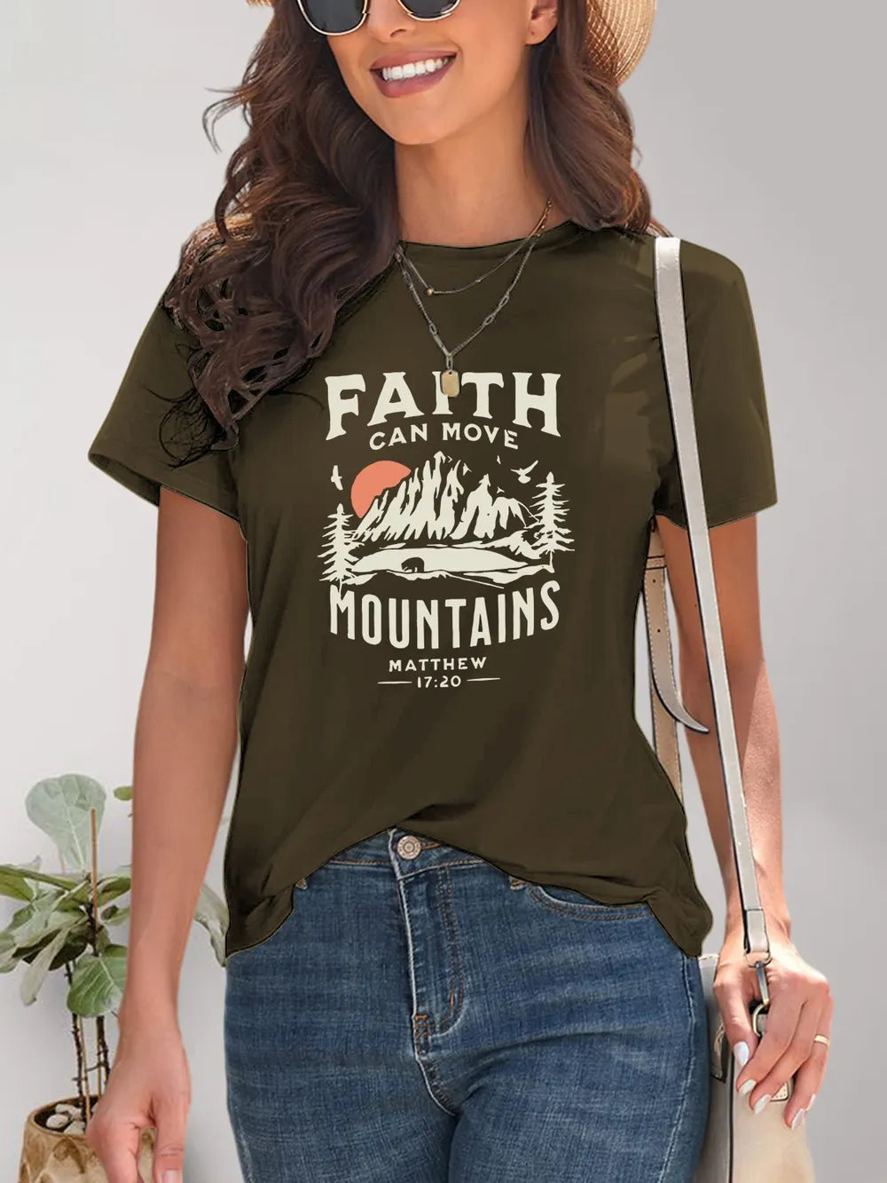 Woman wearing a green t-shirt with 'Faith Can Move Mountains' graphic and text.