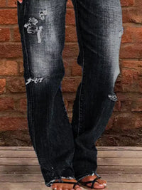 Distressed black jeans worn by a person against a brick wall.