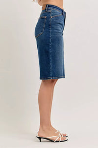 Blue denim skirt worn by a person on a plain background