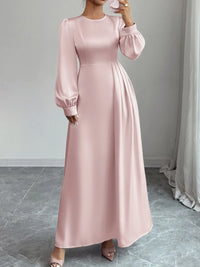 Pink long dress with balloon sleeves worn by a person, standing against a neutral background.