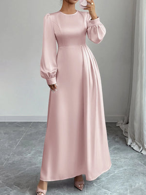 Pink long dress with balloon sleeves worn by a person, standing against a neutral background.