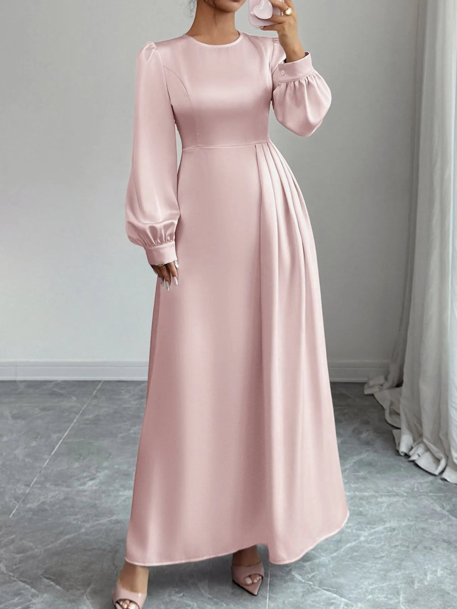 Pink long dress with balloon sleeves worn by a person, standing against a neutral background.