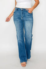 Person wearing blue jeans and a white top on a plain background