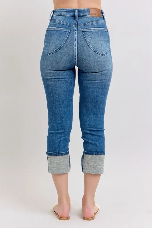 Blue jeans with rolled-up cuffs on a plain background