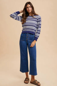 Woman wearing a striped sweater and blue jeans on a beige background