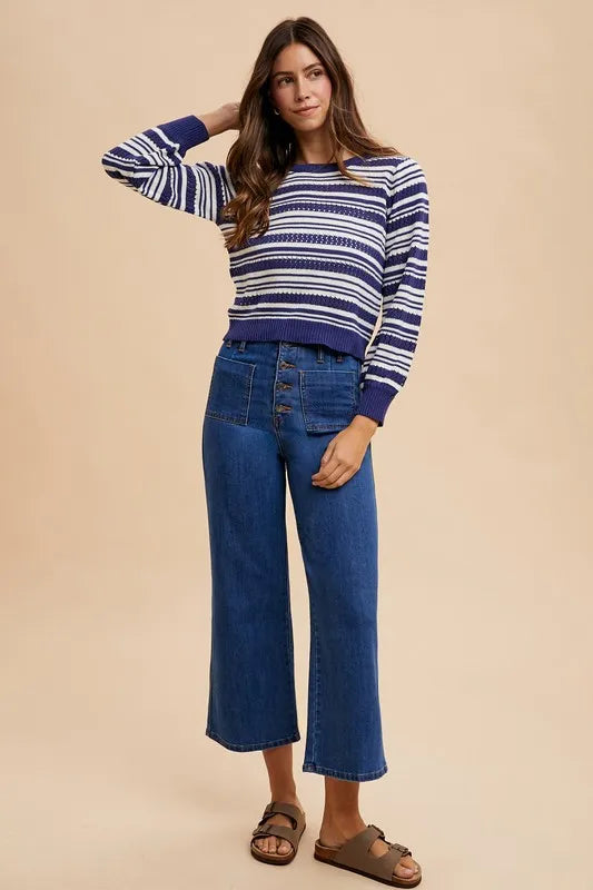 Woman wearing a striped sweater and blue jeans on a beige background