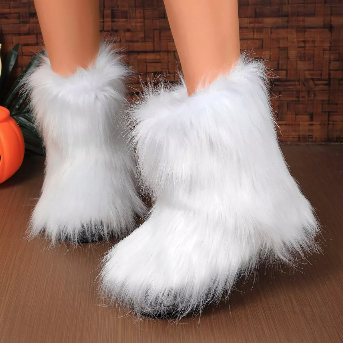 White fluffy boots on a wooden floor with a wicker basket in the background.