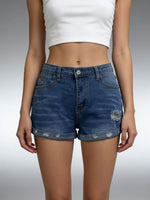 Person wearing blue denim shorts and a white crop top on a gray background